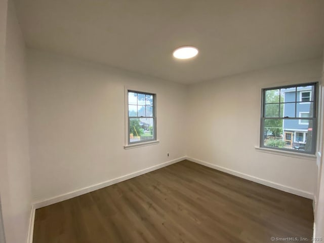 spare room with a healthy amount of sunlight, dark wood-style flooring, and baseboards