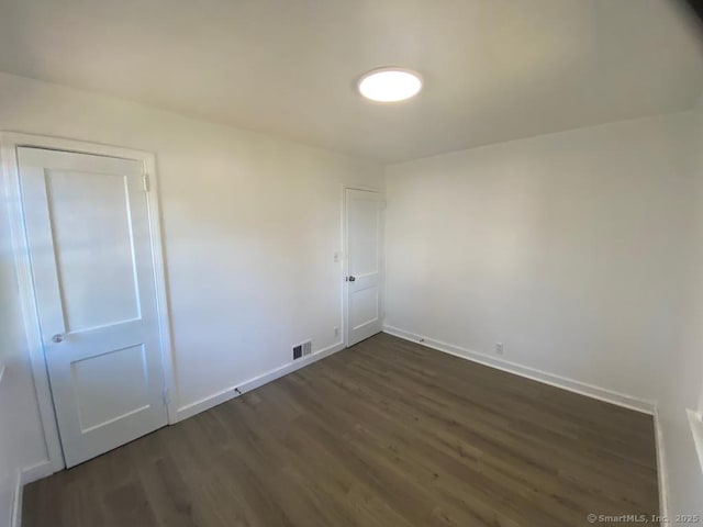 spare room with visible vents, dark wood finished floors, and baseboards