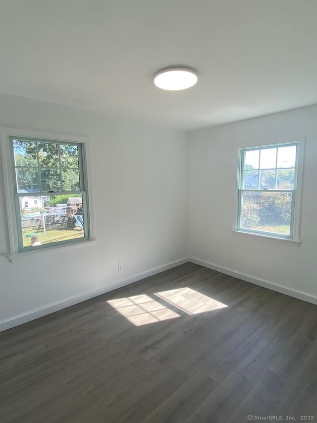 spare room featuring dark wood finished floors and baseboards