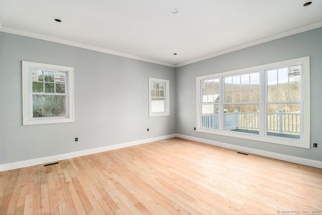 empty room with light hardwood / wood-style flooring, plenty of natural light, and crown molding