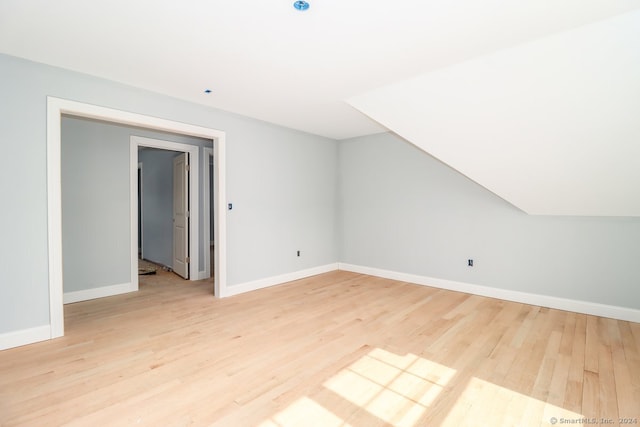 additional living space featuring light wood-type flooring and vaulted ceiling