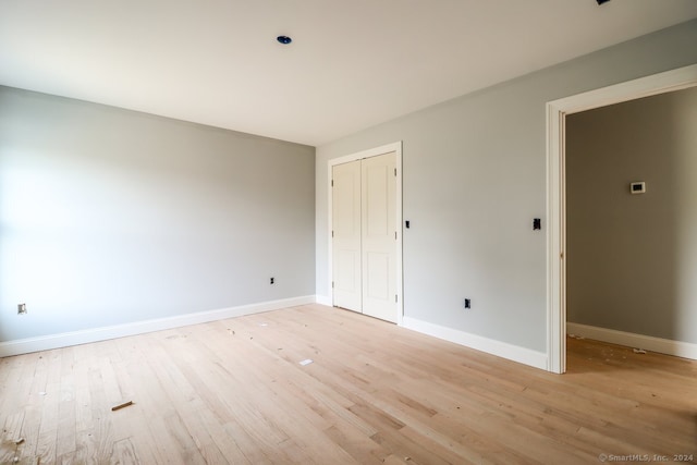 unfurnished bedroom with light hardwood / wood-style flooring and a closet