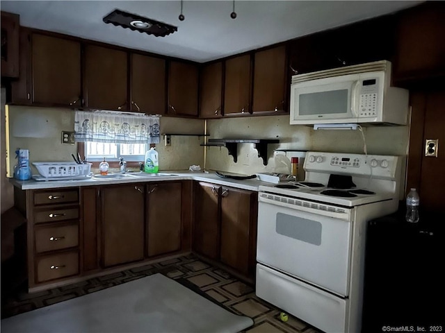 kitchen with dark brown cabinets, white appliances, and sink