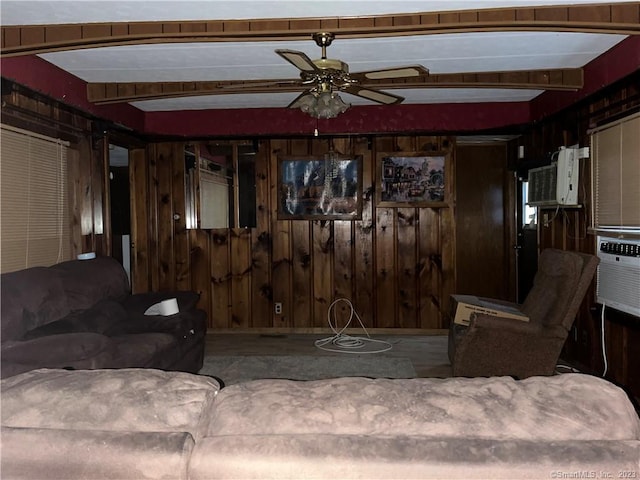 living room featuring beamed ceiling, wooden walls, and ceiling fan