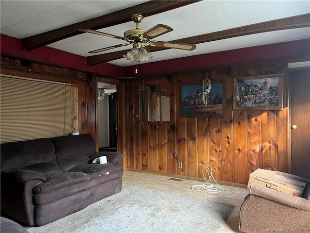 living room with ceiling fan, wooden walls, light wood-type flooring, and beam ceiling