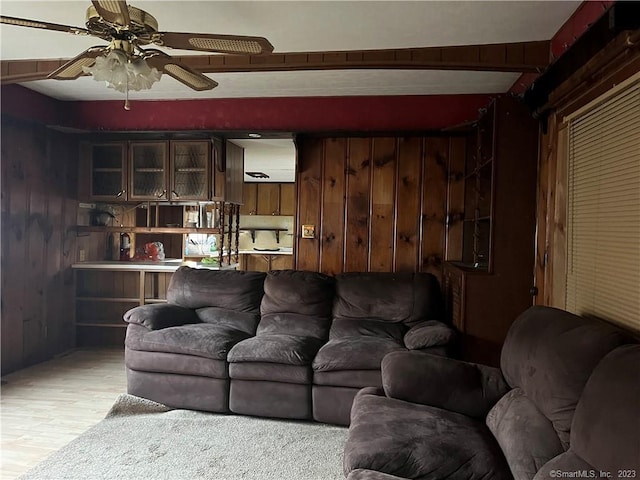 living room with ceiling fan, wooden walls, and light hardwood / wood-style flooring