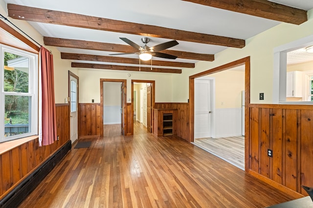 empty room with ceiling fan, dark hardwood / wood-style floors, beam ceiling, and a baseboard heating unit