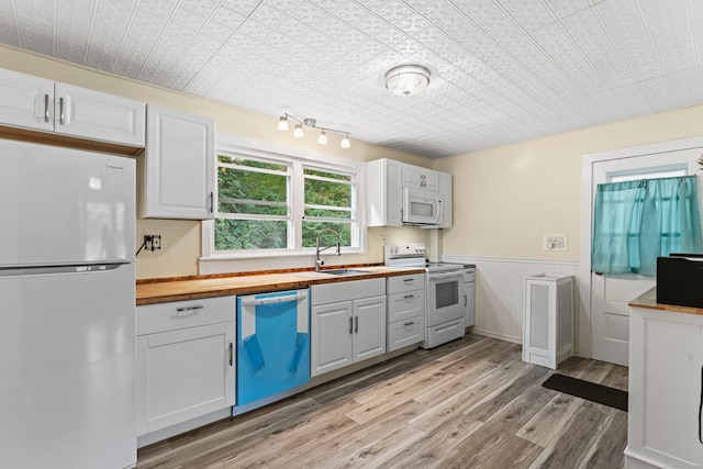 kitchen with white cabinets, white appliances, butcher block counters, and sink