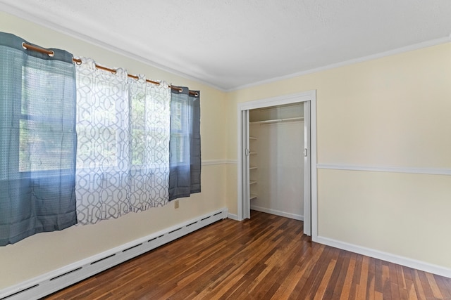 unfurnished bedroom featuring a baseboard heating unit, a closet, dark hardwood / wood-style floors, and crown molding