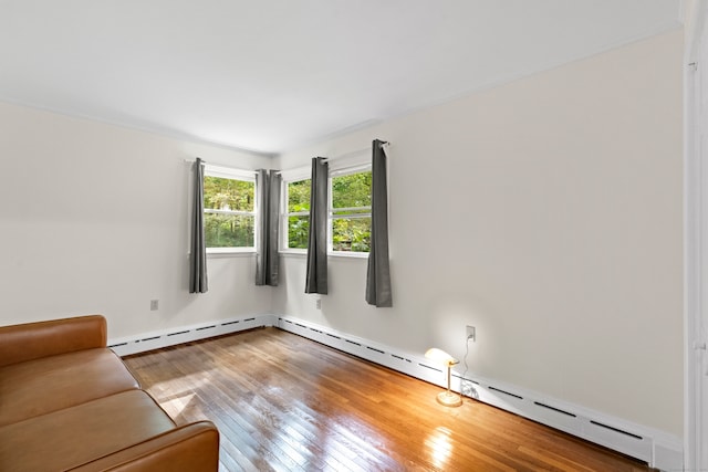 unfurnished room featuring hardwood / wood-style floors and a baseboard heating unit