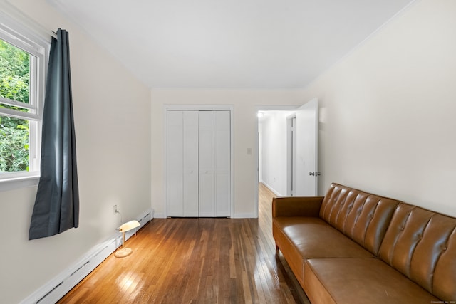 unfurnished living room with crown molding, hardwood / wood-style floors, and a baseboard heating unit