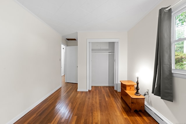 bedroom with crown molding, a closet, dark hardwood / wood-style floors, and a baseboard heating unit