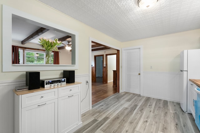 kitchen featuring white cabinets, white refrigerator, light wood-type flooring, and butcher block counters