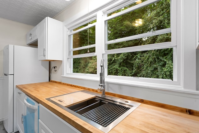 kitchen with white cabinets, sink, white appliances, wooden counters, and hardwood / wood-style flooring