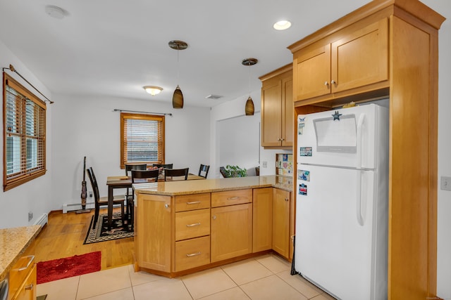 kitchen featuring hanging light fixtures, kitchen peninsula, light stone countertops, white fridge, and light hardwood / wood-style flooring