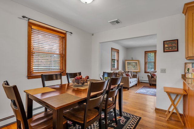 dining area featuring a baseboard radiator, light hardwood / wood-style floors, and a healthy amount of sunlight