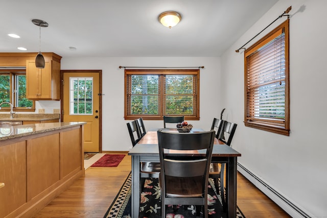 dining room with a baseboard radiator, light hardwood / wood-style flooring, and plenty of natural light