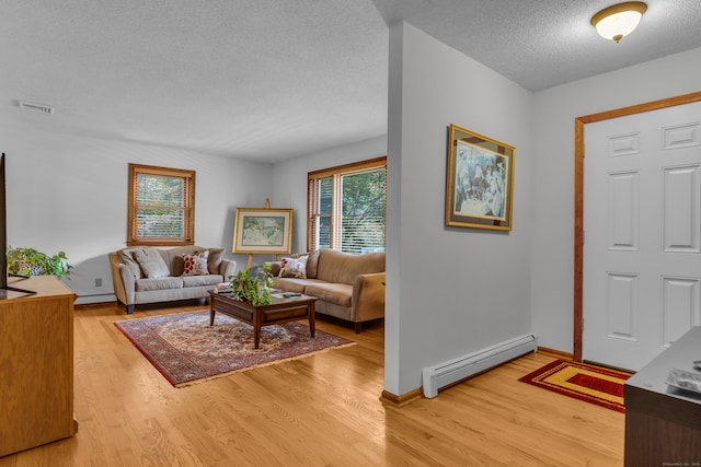 foyer entrance with a baseboard radiator, light hardwood / wood-style floors, and a textured ceiling