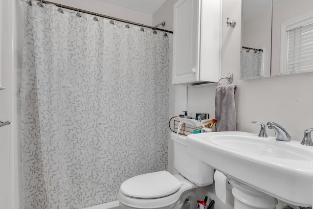 bathroom featuring toilet, sink, and a shower with curtain