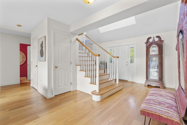 foyer with wood-type flooring and a skylight