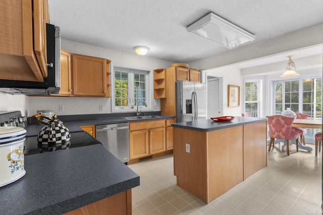 kitchen with a wealth of natural light, a kitchen island, sink, and appliances with stainless steel finishes