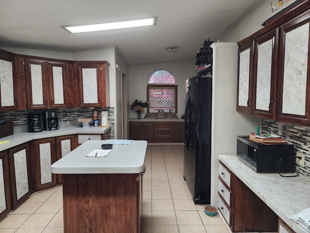 kitchen with black appliances, backsplash, light tile patterned floors, and a kitchen island