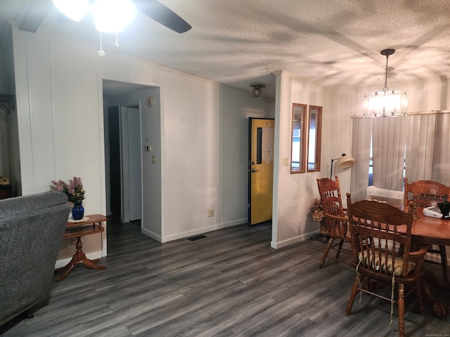 dining area with a textured ceiling, ceiling fan with notable chandelier, and dark wood-type flooring