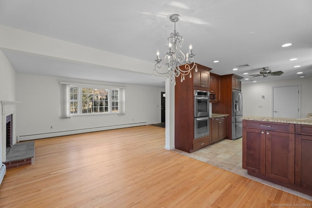 kitchen with a brick fireplace, baseboard heating, appliances with stainless steel finishes, ceiling fan, and light hardwood / wood-style floors