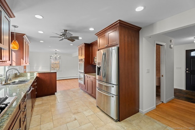 kitchen with pendant lighting, sink, stainless steel appliances, light stone countertops, and ceiling fan with notable chandelier