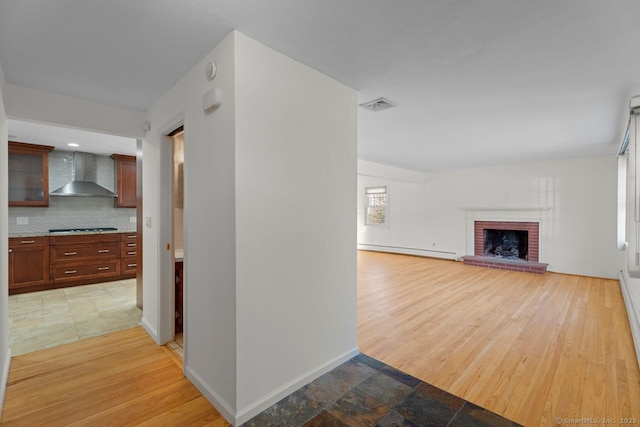 unfurnished living room featuring a baseboard heating unit, wood-type flooring, and a brick fireplace