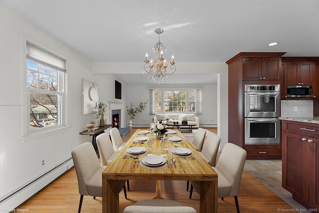 dining space with an inviting chandelier, light hardwood / wood-style floors, and a baseboard heating unit