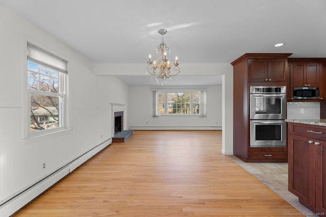 kitchen featuring stainless steel appliances, light stone countertops, a brick fireplace, and a baseboard heating unit