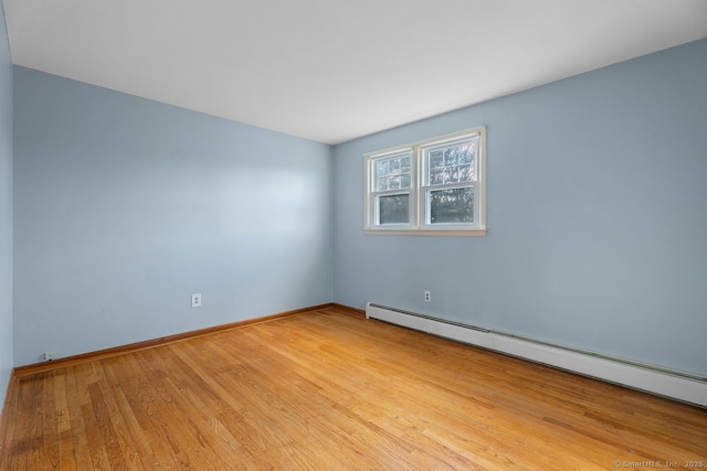 unfurnished room featuring a baseboard radiator and light hardwood / wood-style floors