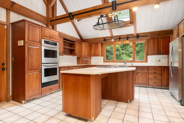 kitchen with beamed ceiling, stainless steel appliances, light tile patterned flooring, and a kitchen island