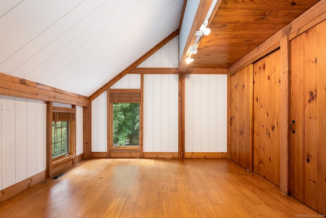 additional living space with light hardwood / wood-style flooring, lofted ceiling, and wood walls