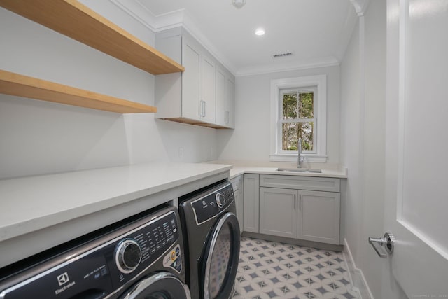 clothes washing area with cabinets, washer and clothes dryer, crown molding, and sink