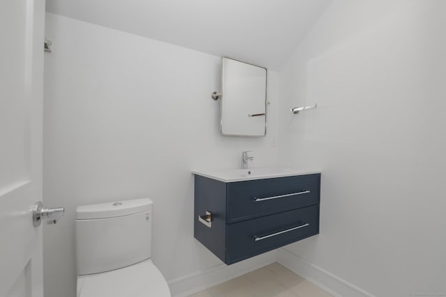 bathroom with tile patterned floors, vanity, toilet, and vaulted ceiling