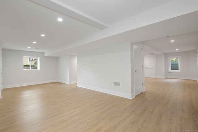 spare room featuring beam ceiling and light hardwood / wood-style flooring