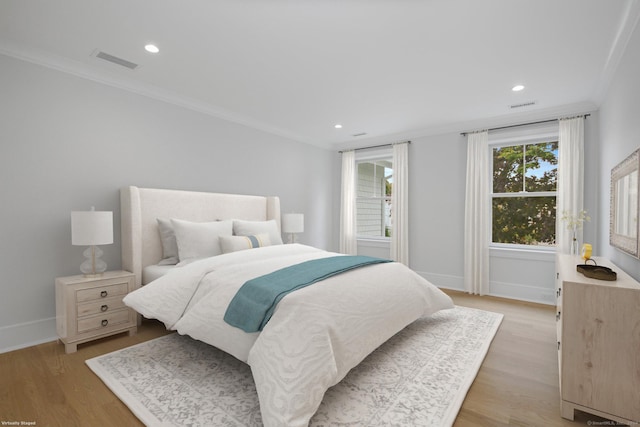 bedroom featuring multiple windows, ornamental molding, and light wood-type flooring