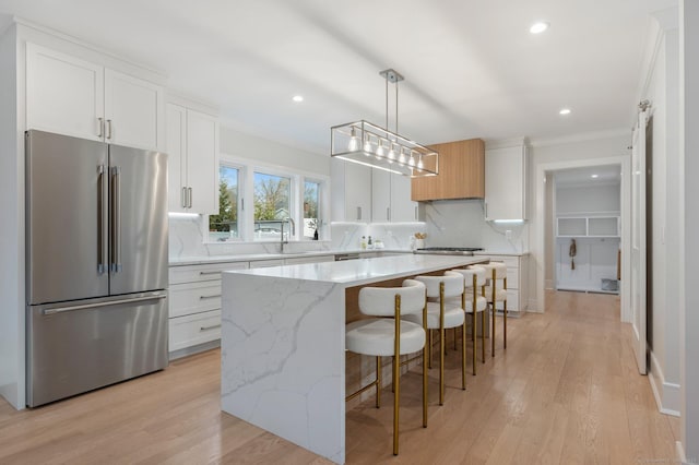 kitchen featuring decorative backsplash, a kitchen island, pendant lighting, white cabinets, and stainless steel refrigerator