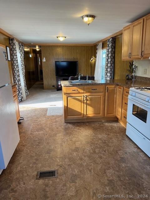 kitchen with kitchen peninsula, wooden walls, sink, and white appliances