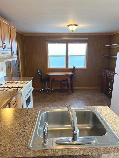 kitchen featuring wooden walls, sink, extractor fan, and white appliances