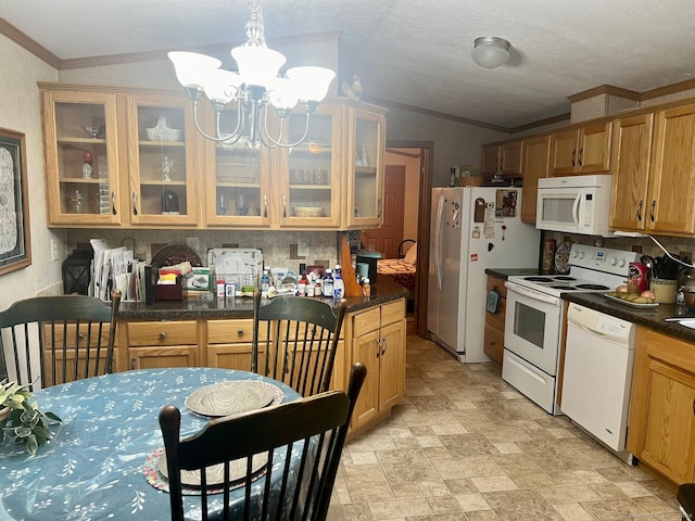 kitchen featuring dark countertops, an inviting chandelier, white appliances, lofted ceiling, and ornamental molding
