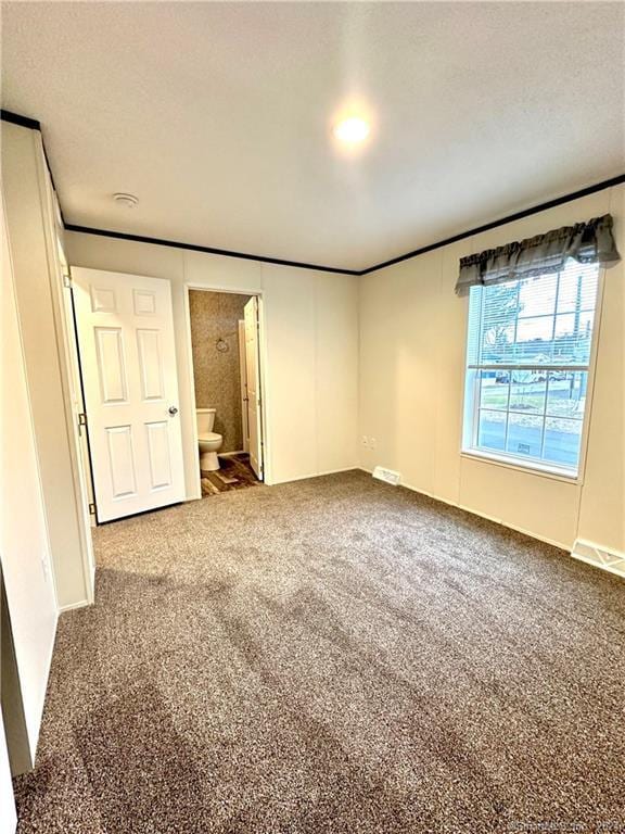 unfurnished bedroom with carpet, a textured ceiling, and ensuite bathroom