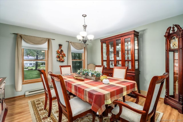 dining area featuring light wood-type flooring, a chandelier, and a baseboard heating unit