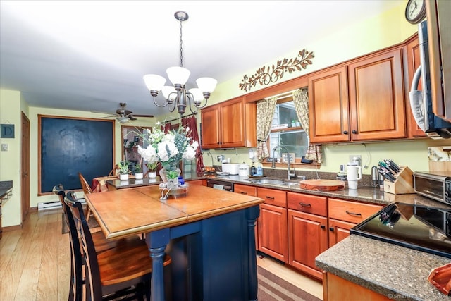 kitchen featuring sink, a kitchen island, decorative light fixtures, ceiling fan with notable chandelier, and light hardwood / wood-style floors