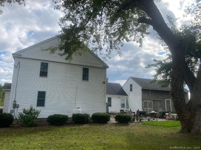 back of property featuring a lawn and a patio