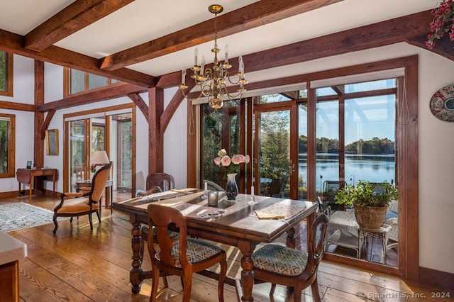 dining room featuring a water view, a notable chandelier, beam ceiling, and wood-type flooring