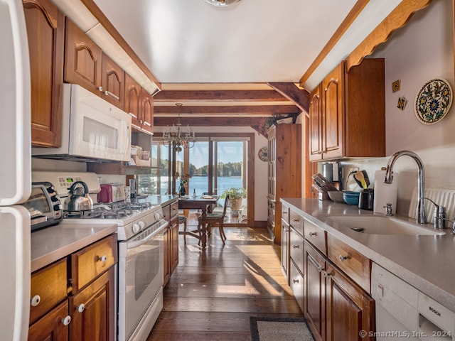 kitchen featuring sink, white appliances, a notable chandelier, dark hardwood / wood-style flooring, and a water view