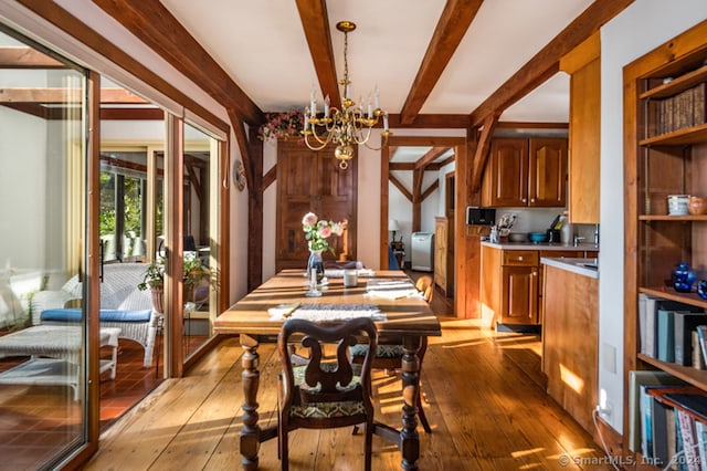 dining area featuring a notable chandelier, light hardwood / wood-style flooring, and beam ceiling